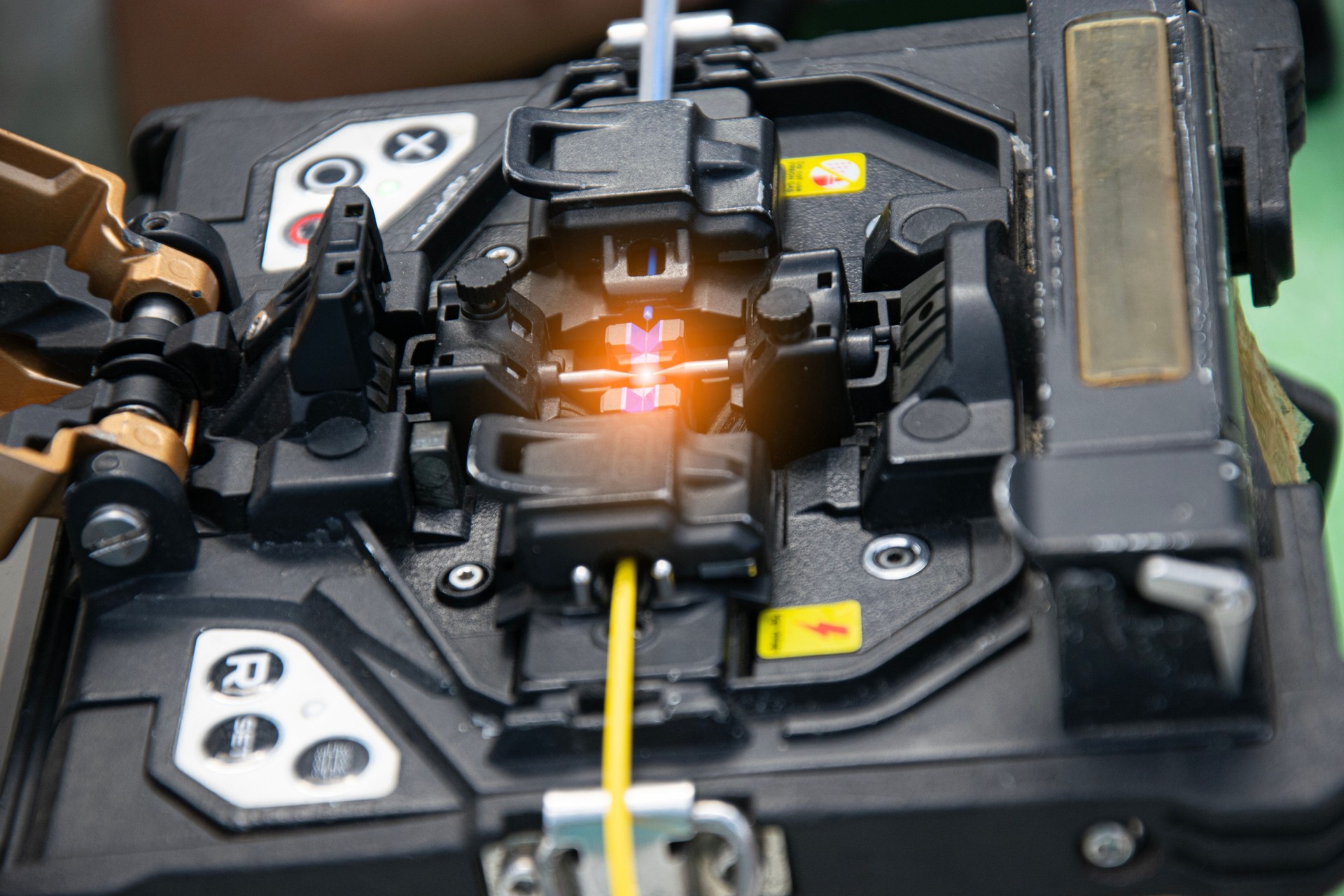 The technician is connecting the fiber optic cable with a tool.